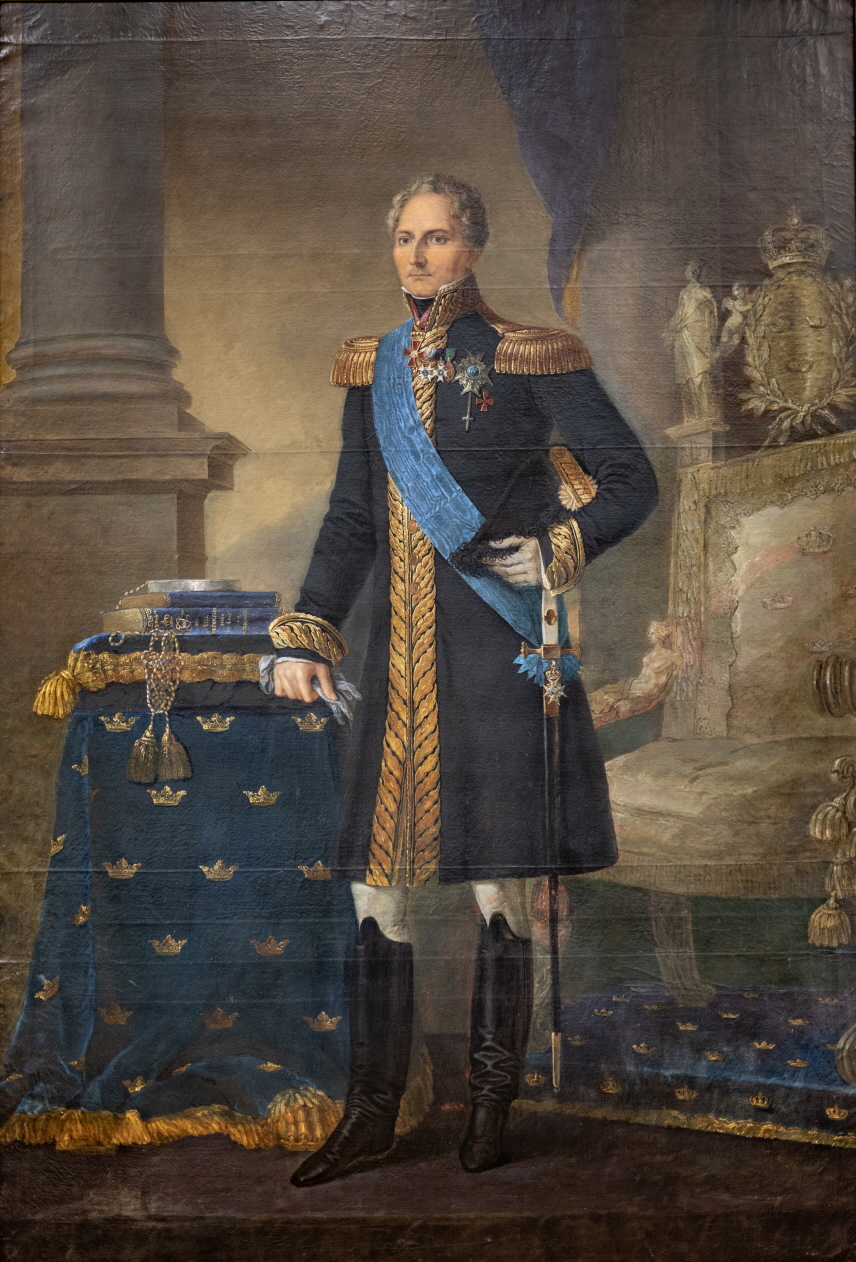 Målning med kung Karl XIV Johan stående i uniform i ett rum med silvertron i bakgrunden.