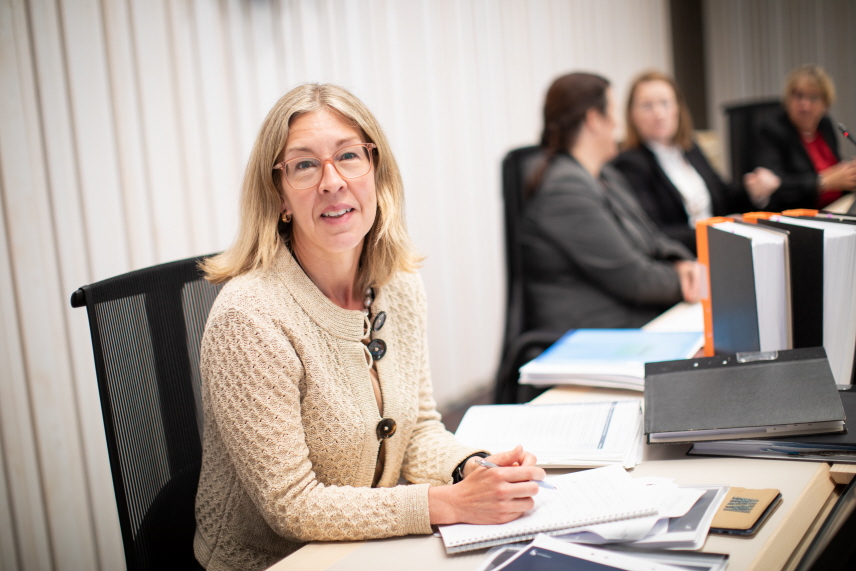 Malin Wik sitter i en rättssal och arbetar. Foto.