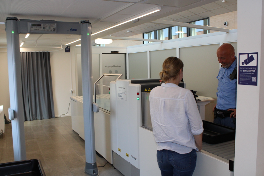 Säkerhetskontroll med besökare som pratar med en ordningsvakt.