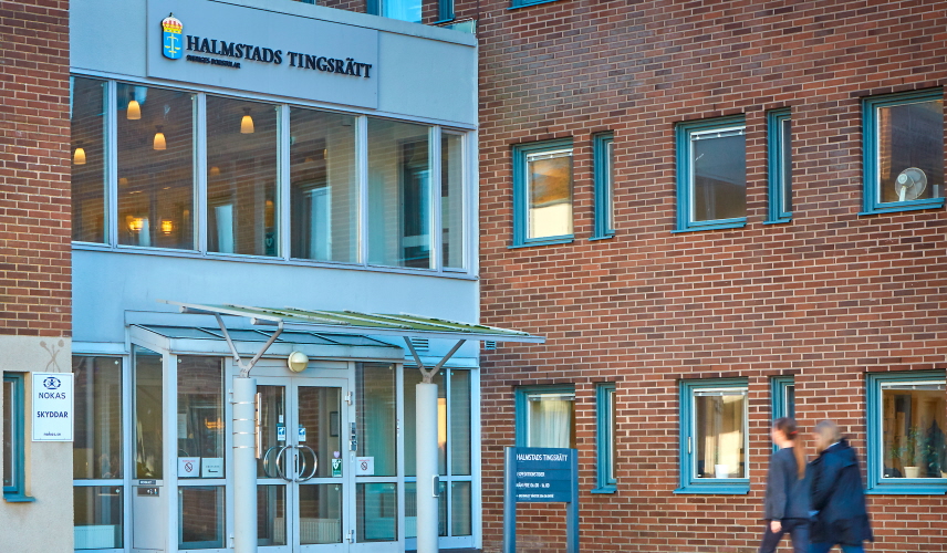 Två personer går mot Halmstad tingsrätts entré