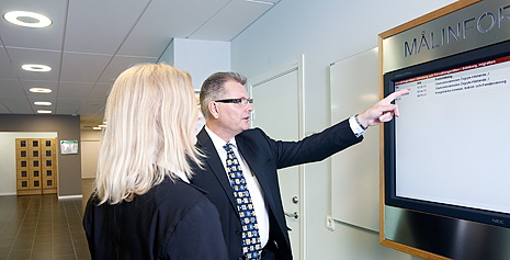 Man pekar på informationstavla. Foto.