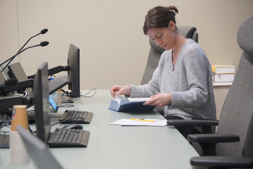 Nämndemannen Madelene San Román sitter i förhandlingssalen och läser lagboken.